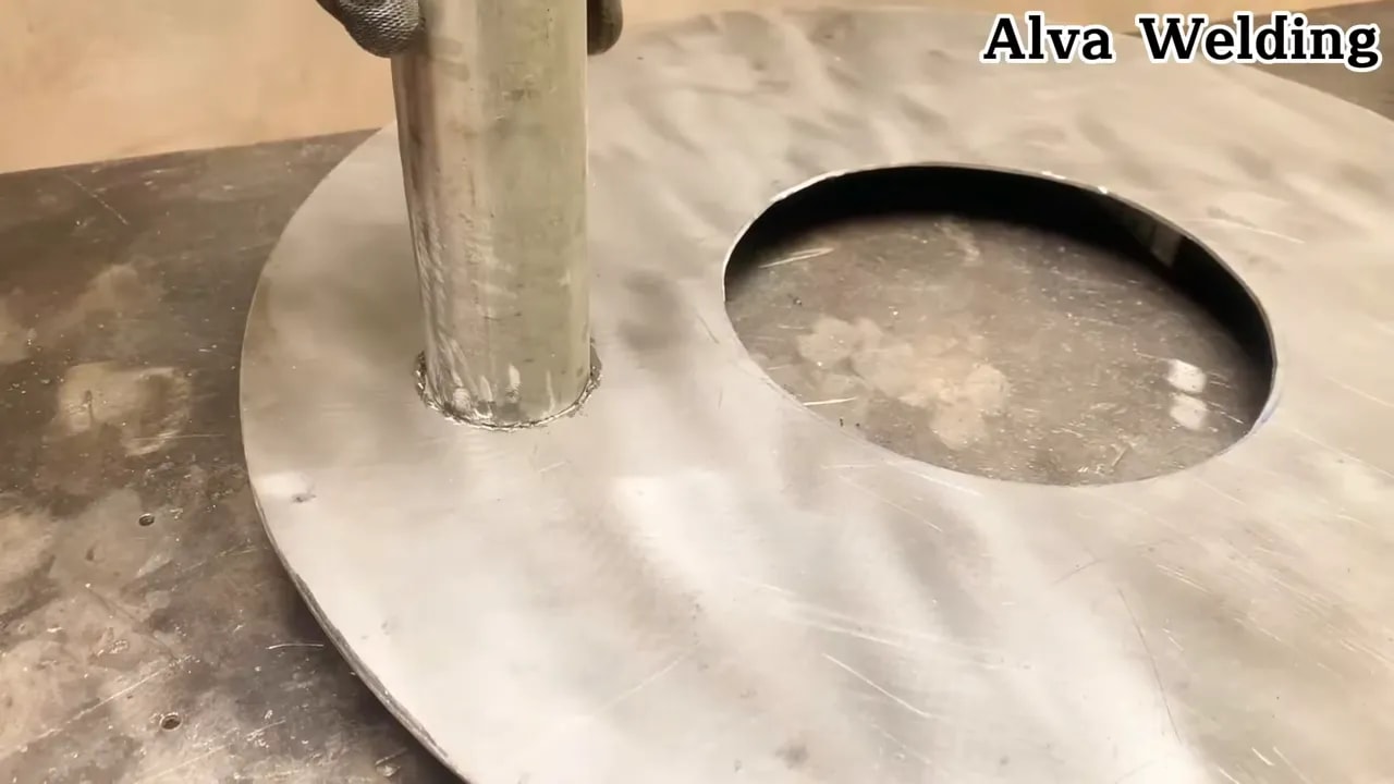 Round metal tube placed upright through a circular hole in a steel plate, ready for welding