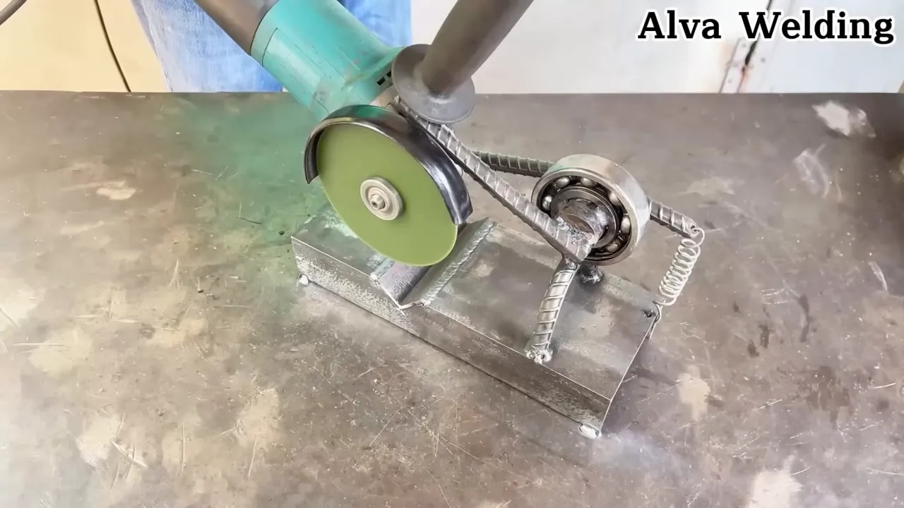 Sliding angle grinder jig with bearings guiding a grinder along rails on a metal workbench